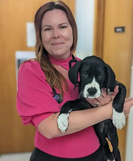 a woman holding a dog posing for the camera